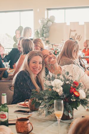 A celebratory gathering with floral centerpieces and champagne glasses on decorated tables.