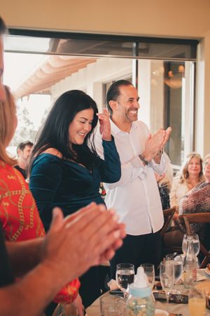 People clapping and celebrating at a social gathering with dining table setup.