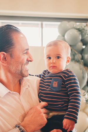 Sweet moment captured at baby shower with balloon decor in background.