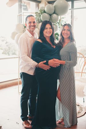 Maternity photo with elegant navy dress against balloon arch backdrop.