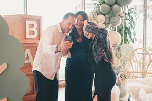 Friends and family pose together at a celebration with white balloon decorations.