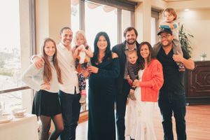 Family members gather for casual photos in a brightly lit room with hardwood floors.