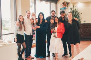 Group celebration photos in front of large windows with white balloon decorations.