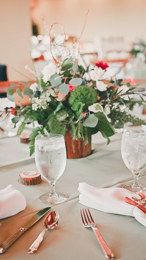 Elegant table setting with floral centerpieces, white linens, and rose gold cutlery.