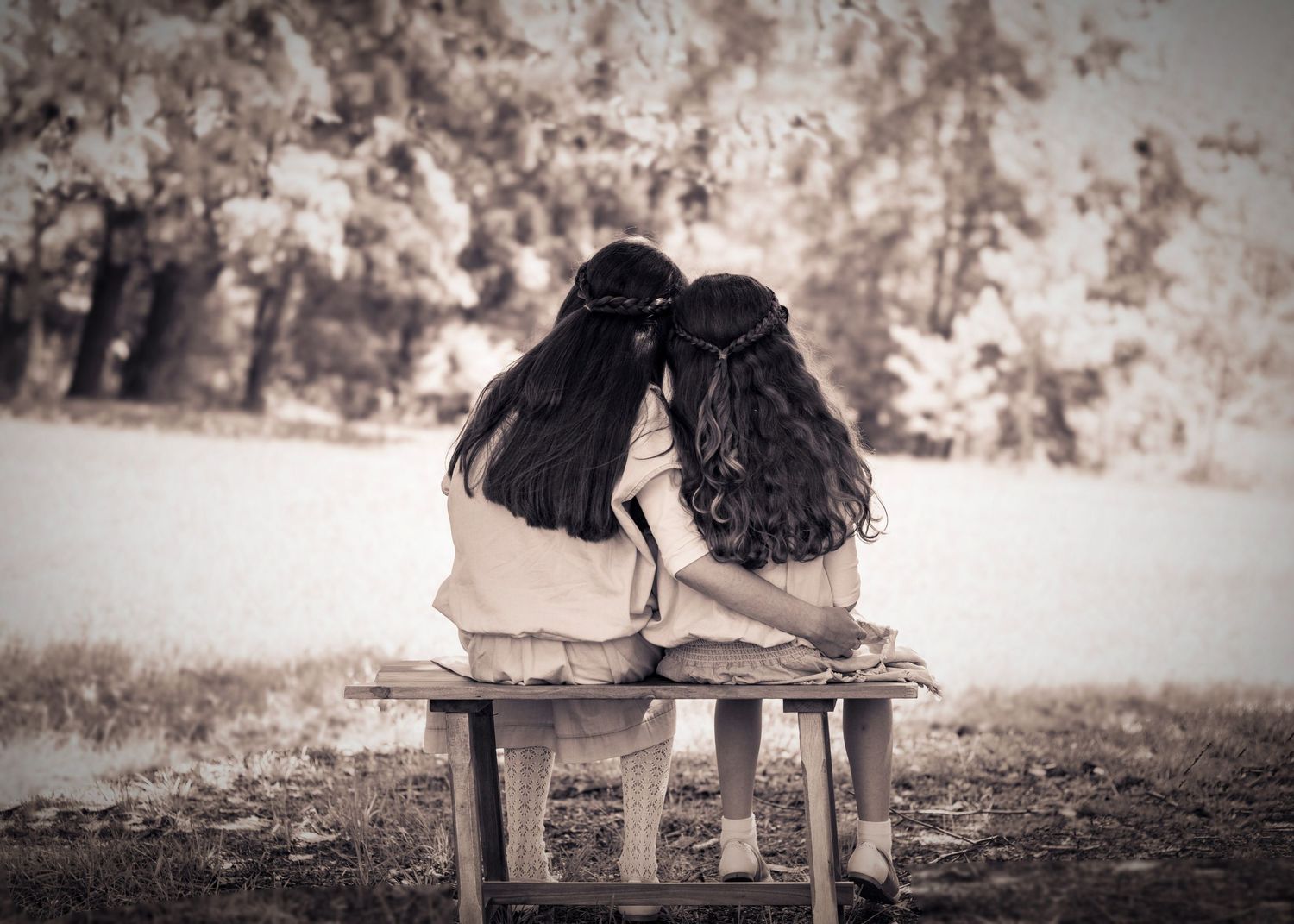 monochromatic photo of two sisters sharing a sweet moment together on a vintage bench