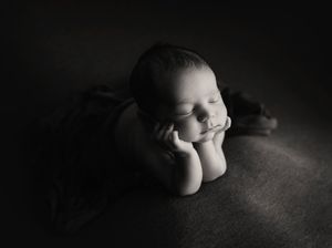 Black and white portrait of sleeping baby on textured surface.