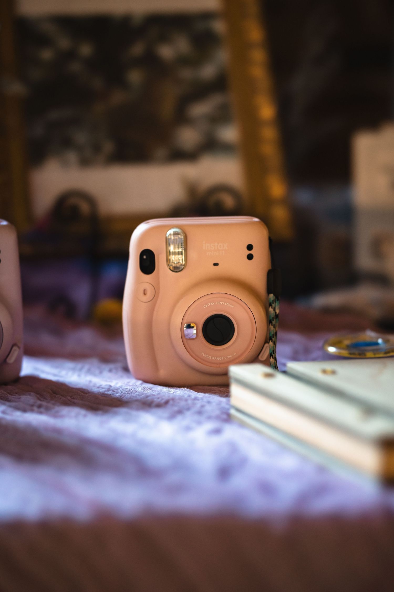 A peach-colored Fujifilm Instax Mini instant camera on a textured surface.