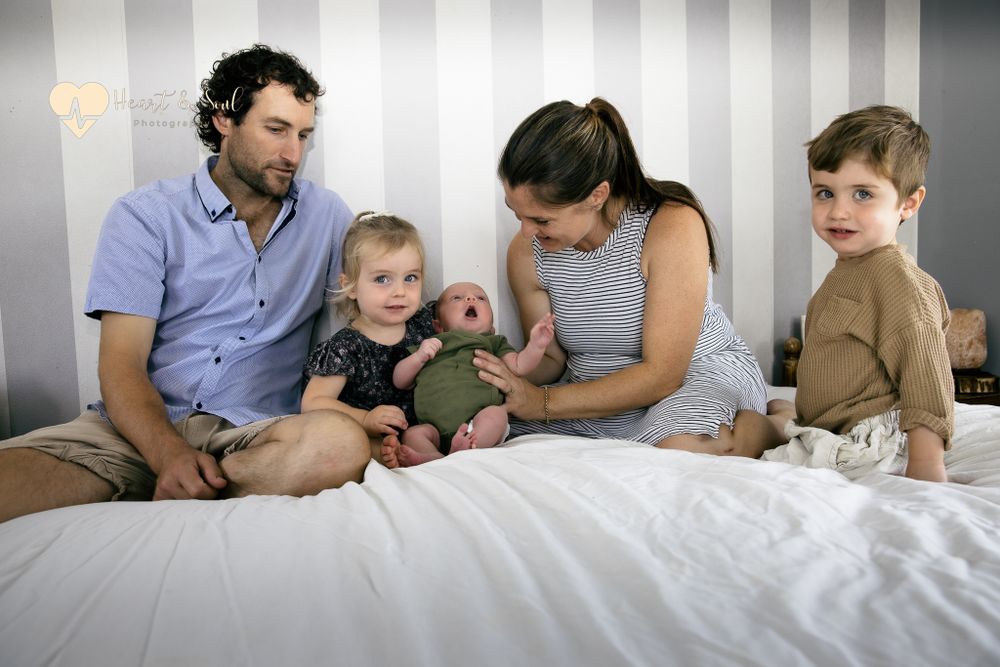 lady and man with 2 kids and baby on a bed