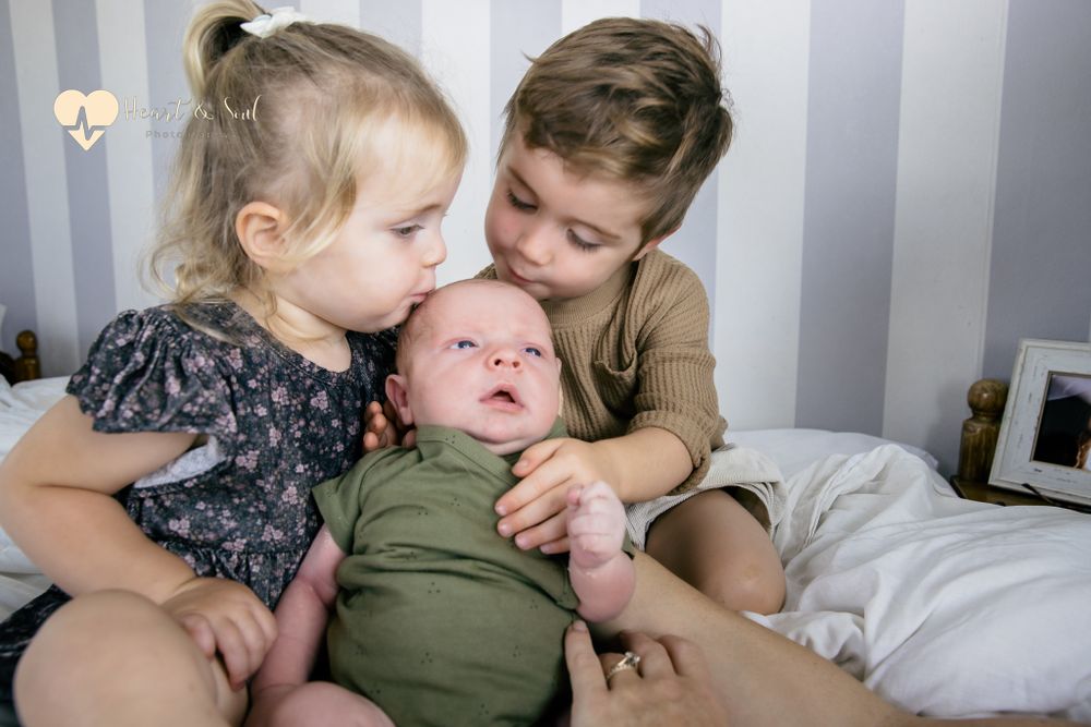 two kids kissing baby head