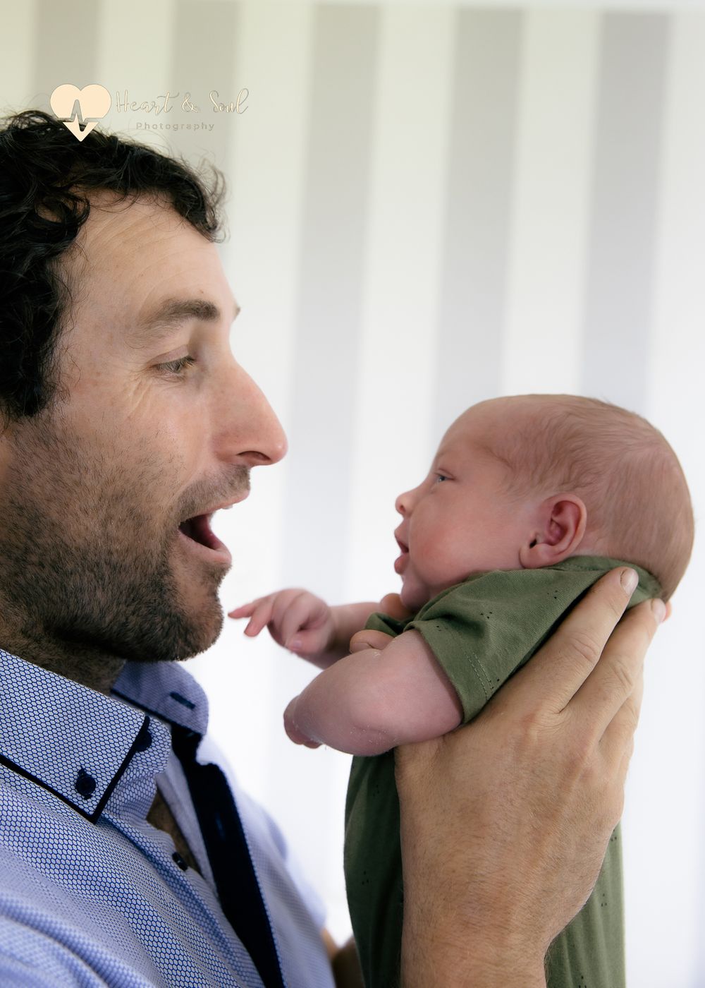 man pulling faces while holding baby