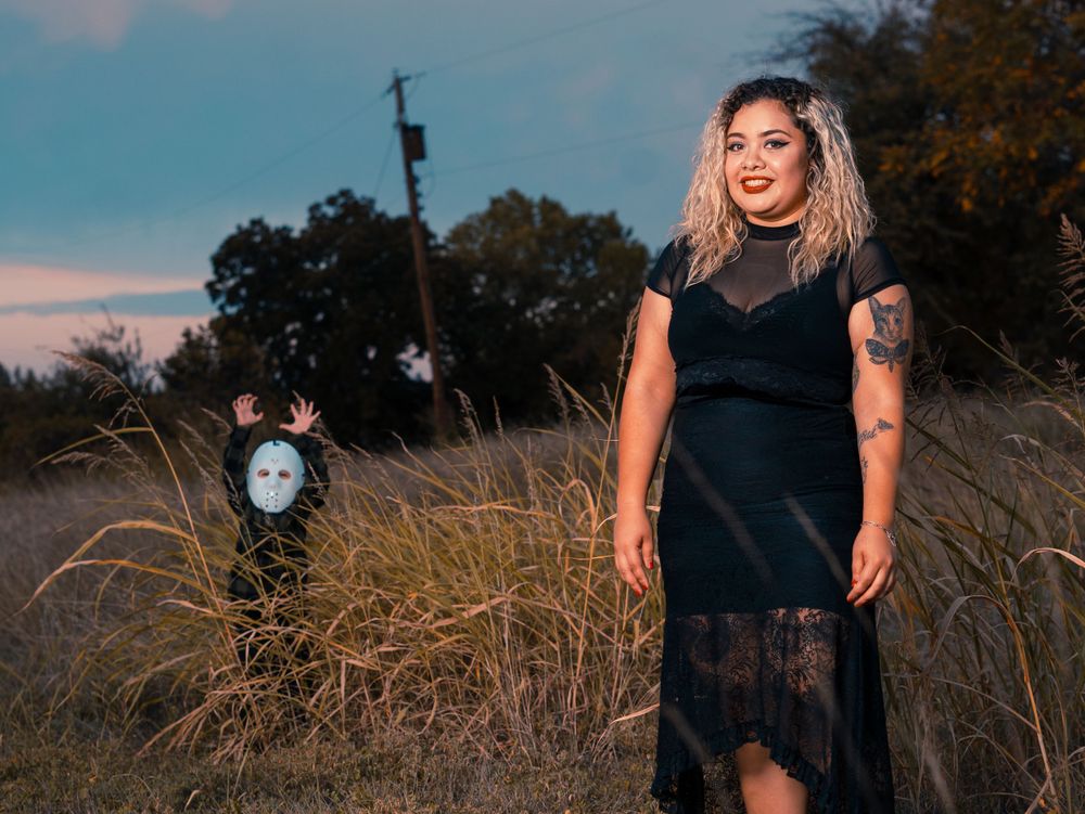 A black lace dress stands out against tall grass and sunset sky at golden hour.