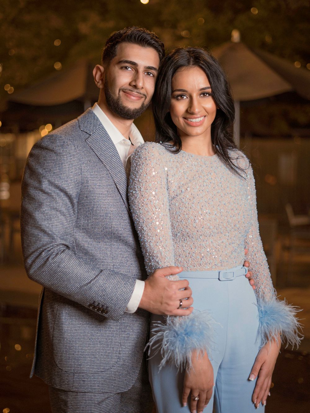 Formal portrait featuring grey suit and light blue outfit with feather details.