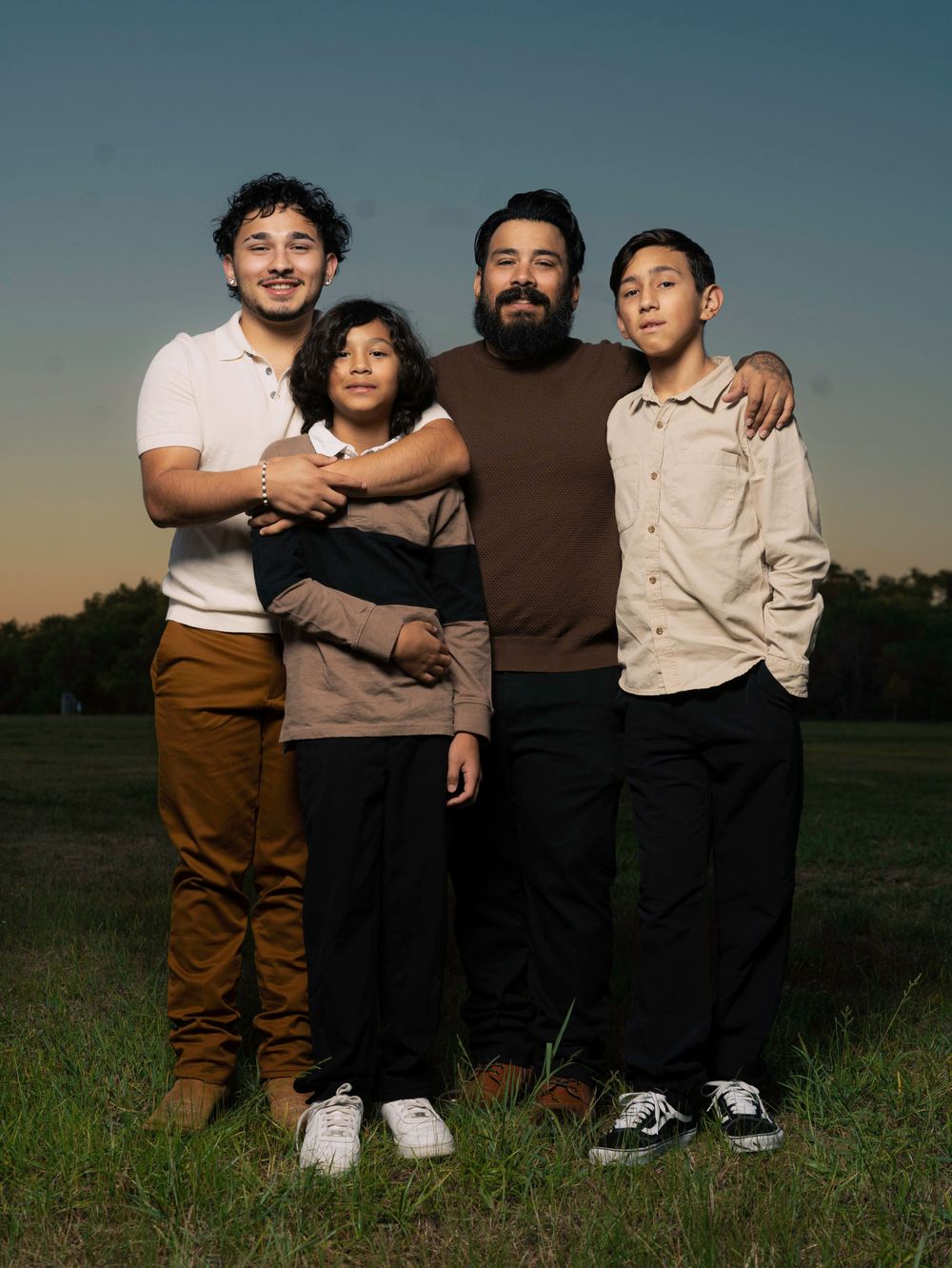 A group portrait taken outdoors against a sunset sky in casual attire.