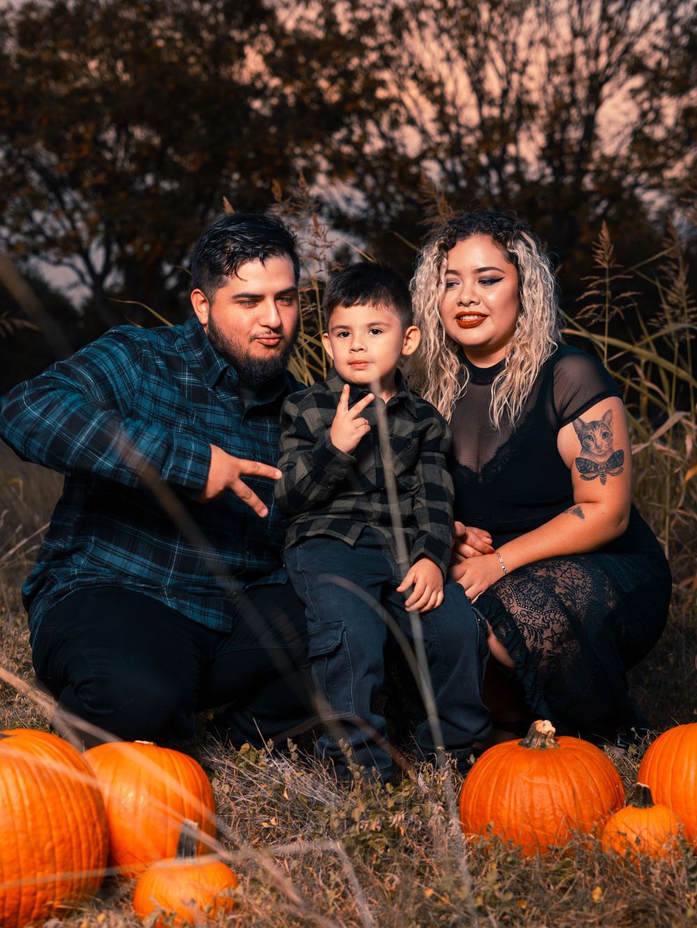 Family making fun poses among pumpkins during sunset photo session.