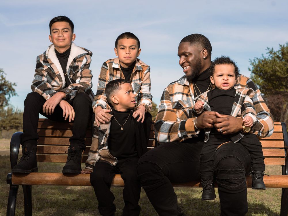 Group sitting on wooden bench wearing matching plaid jackets during outdoor photo session.