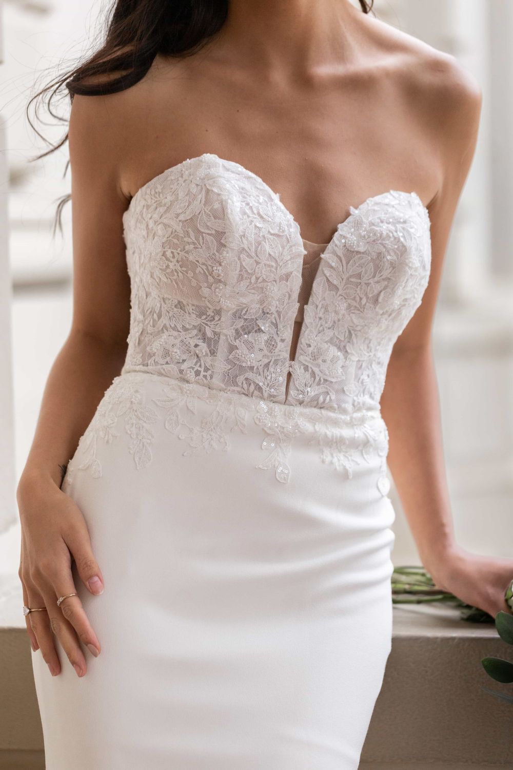 Close-up detail of strapless sweetheart lace corset bodice on fitted white wedding dress.