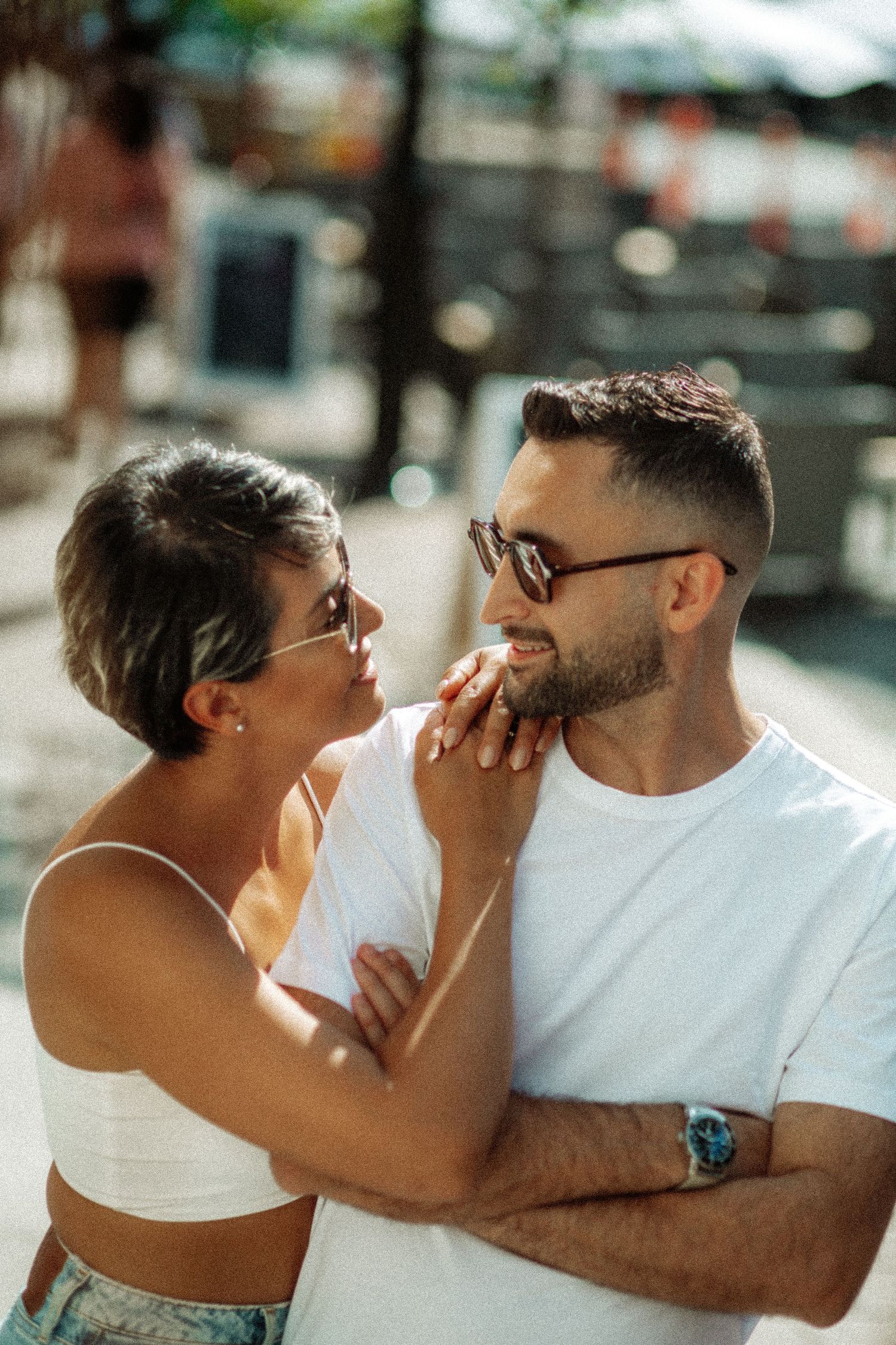 A romantic couple in casual summer attire sharing an intimate moment outdoors in natural lighting.