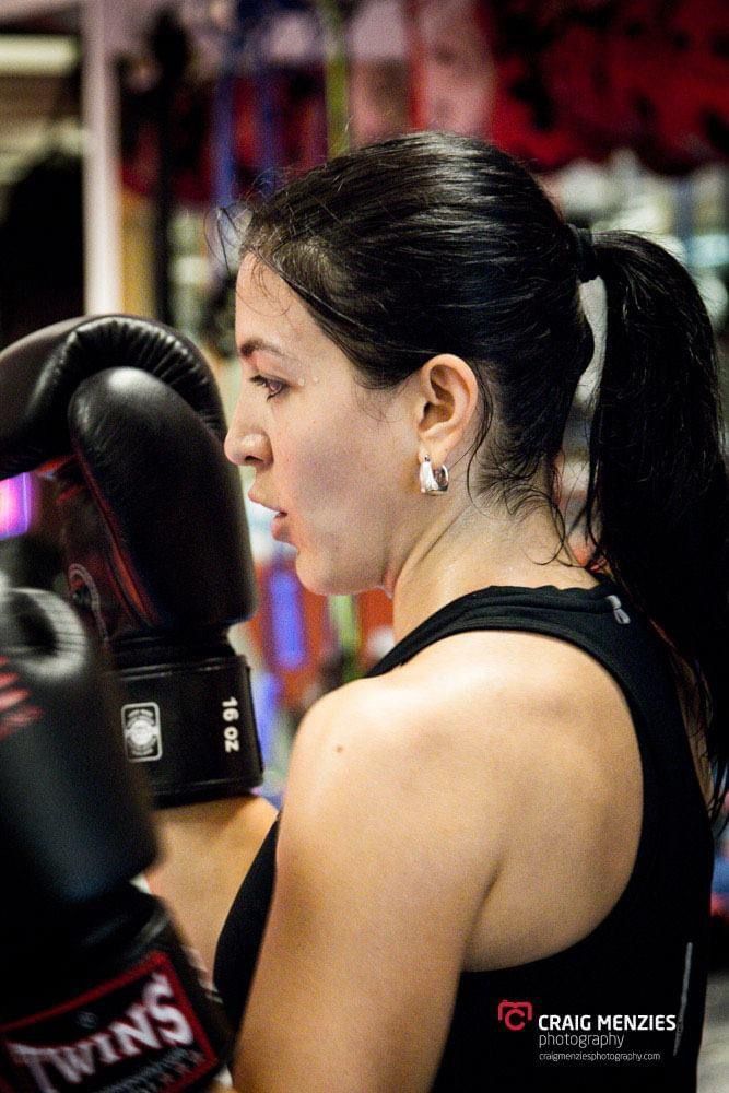 Close-up profile of female boxer with Twins 16oz boxing gloves during training session.