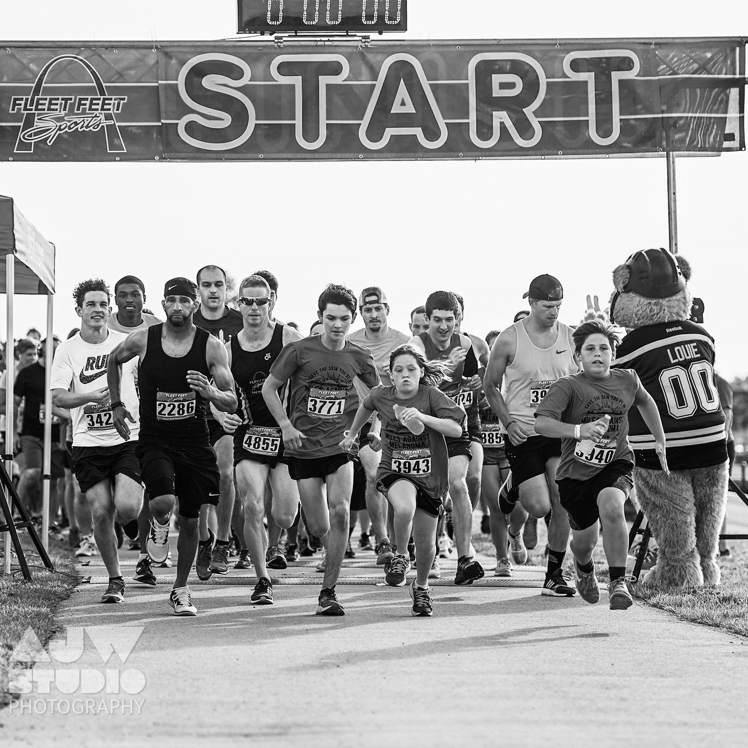 Group of runners at the starting line of a race under a banner marked START.