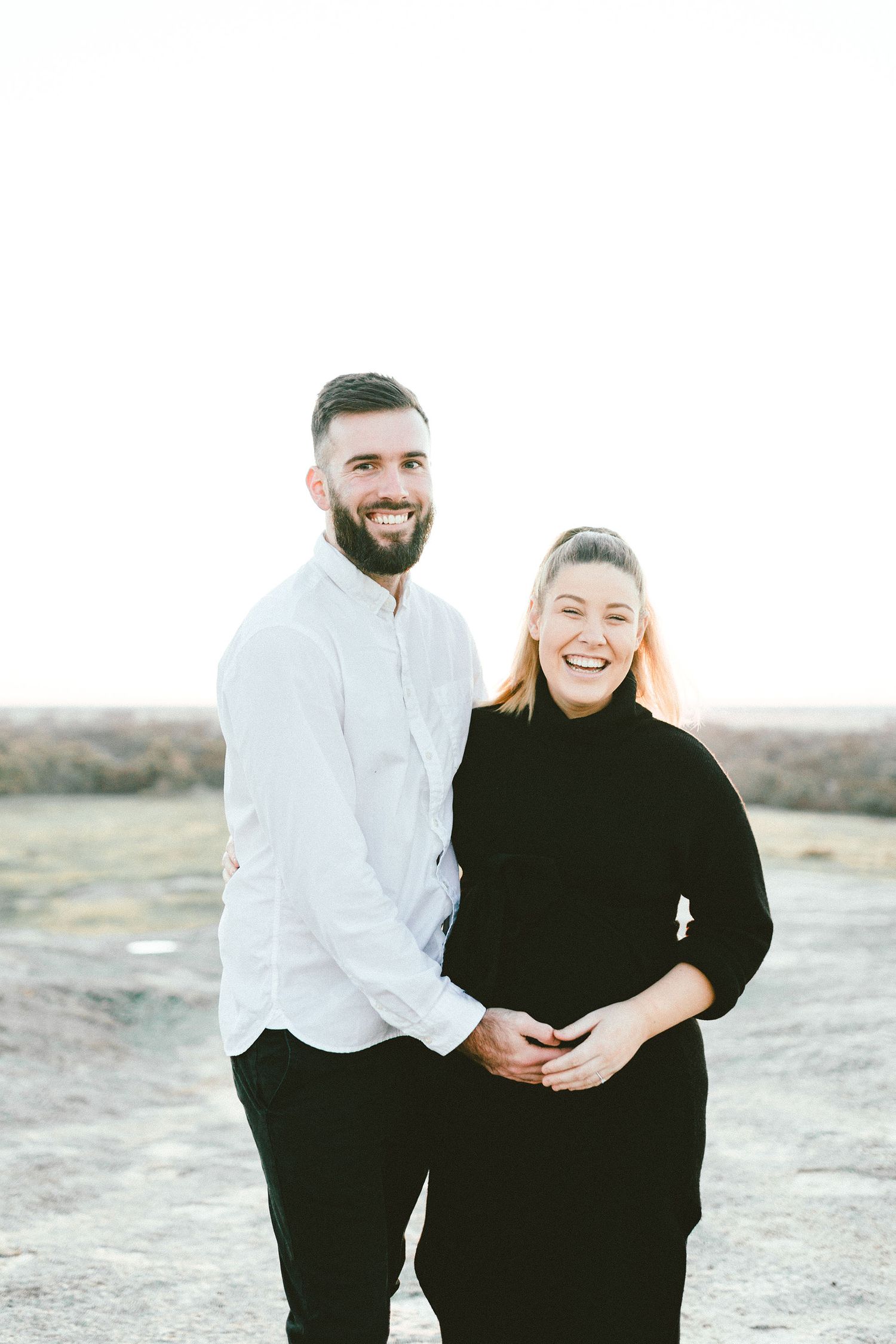 A couple in contrasting black and white outfits posing together outdoors.