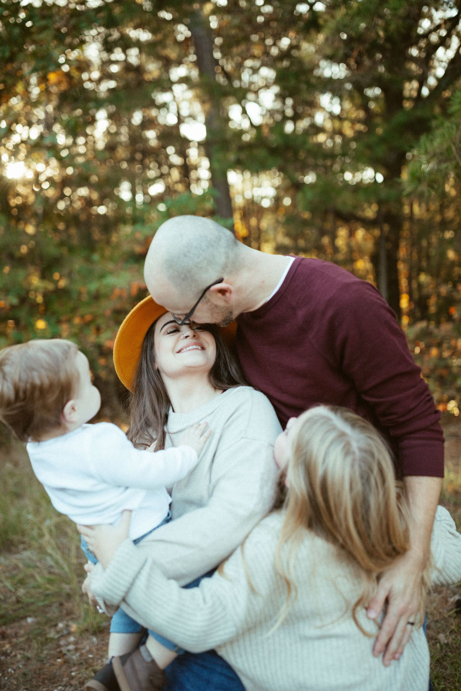 A loving family moment captured in autumn woods during golden hour.