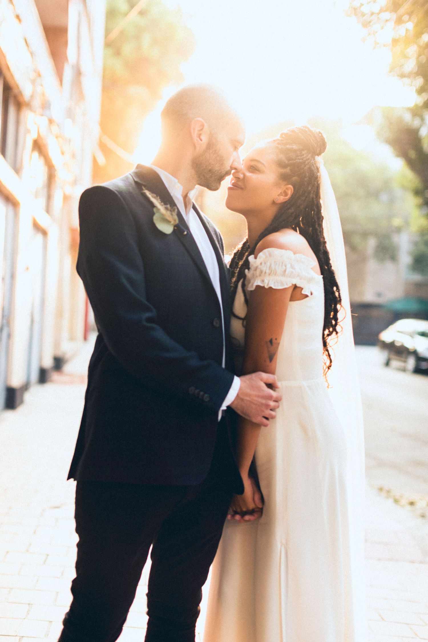 A romantic wedding couple sharing an intimate moment on a city street at sunset.