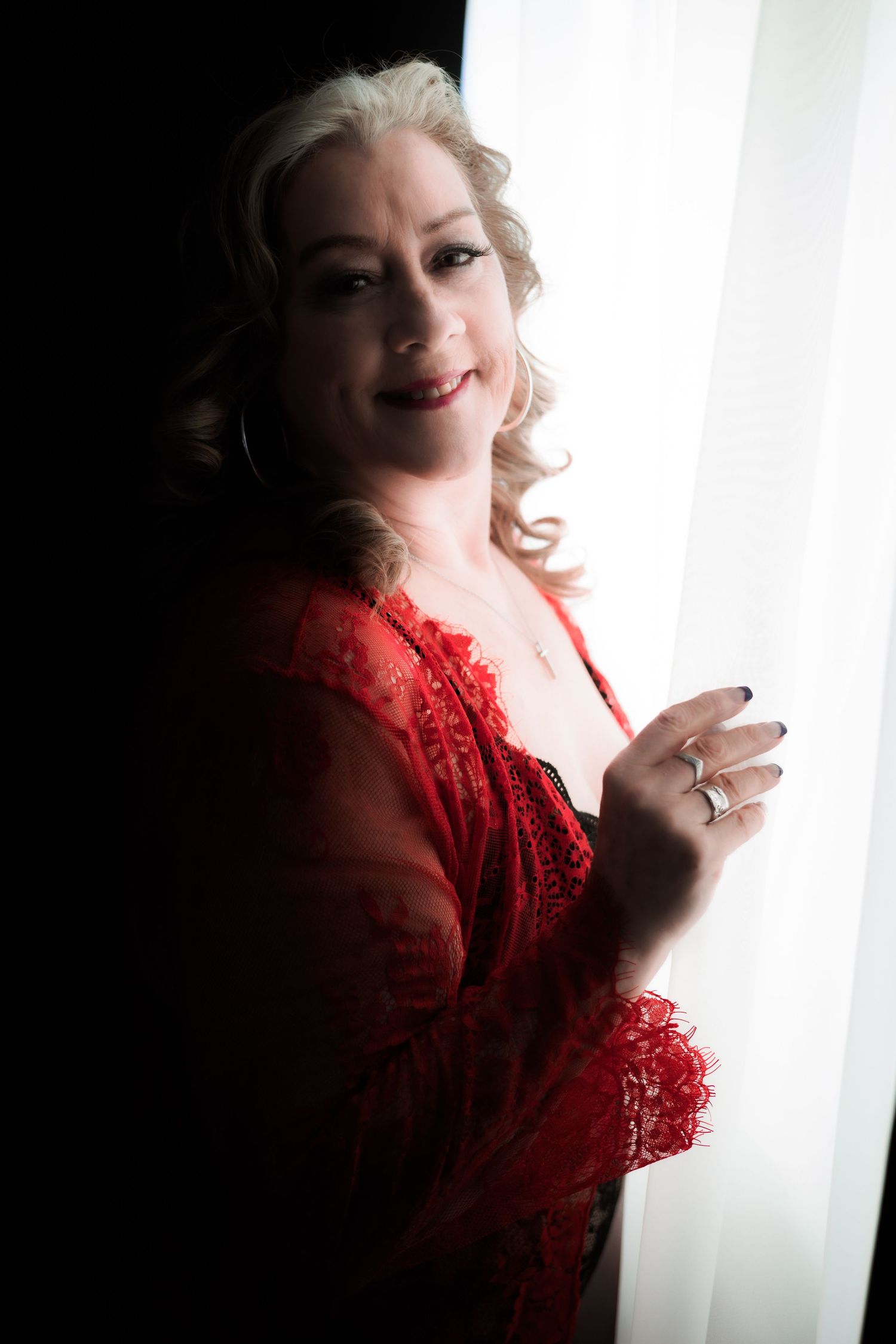 Side view portrait of woman in red lace by window with natural light.