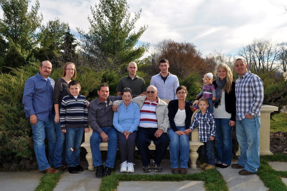 Large family group portrait outdoors with multiple generations standing together.
