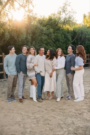 Group portrait of friends laughing together outdoors in coordinated neutral outfits.
