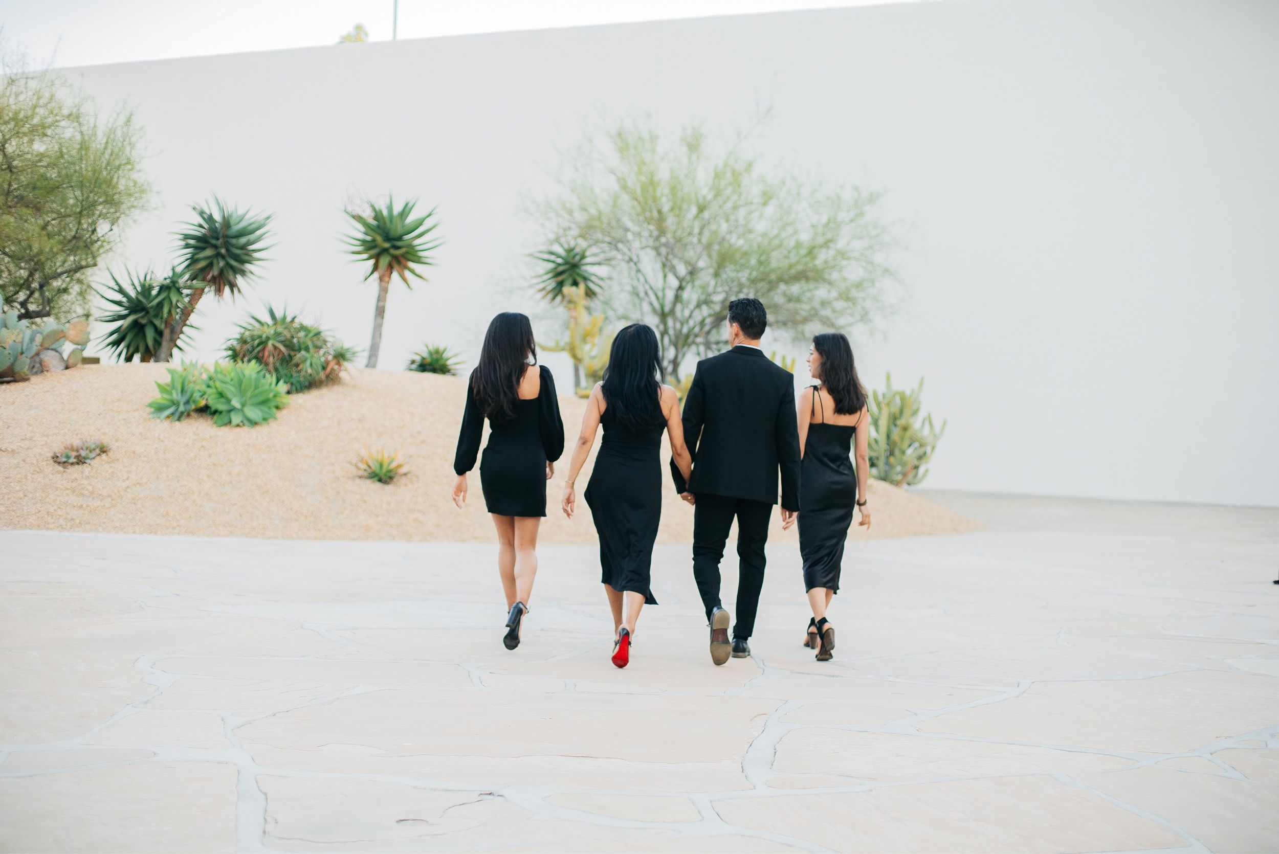 Group of people walking together into distance on desert path.