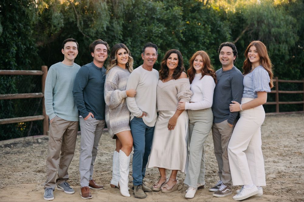 Group photo of friends wearing coordinated neutral colors standing together outdoors.