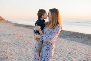 Sweet sunset beach moment between parent and child in floral dress.