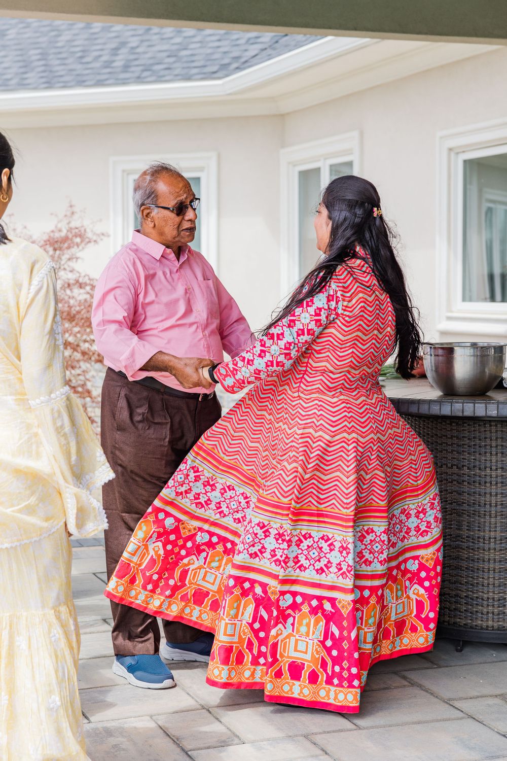 Guests in colorful traditional attire at a celebration gathering on an outdoor patio.