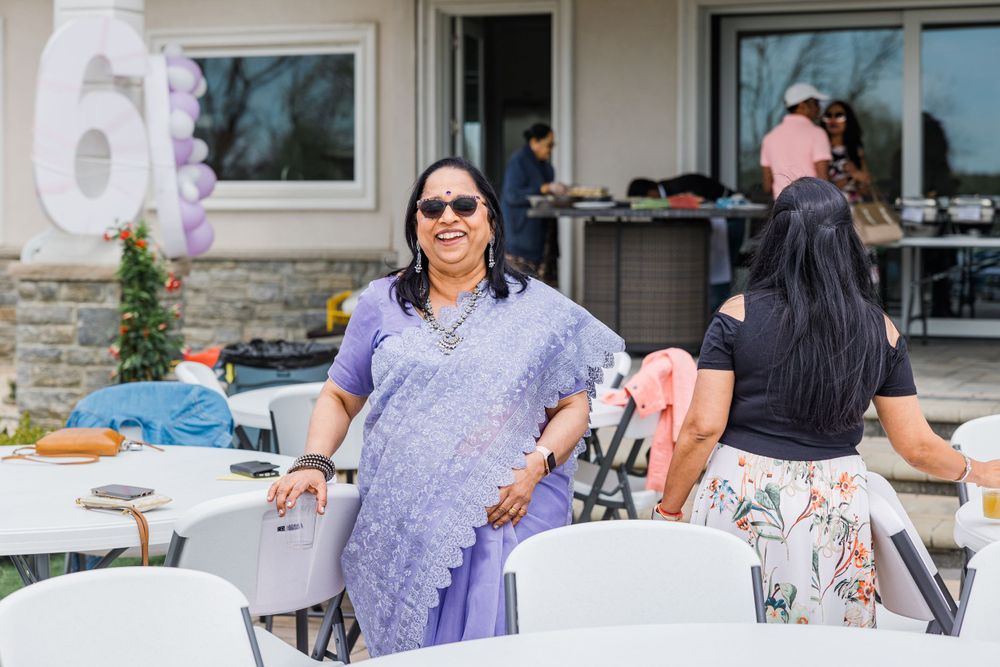 Person in a purple sari standing by outdoor party decorations and chairs.
