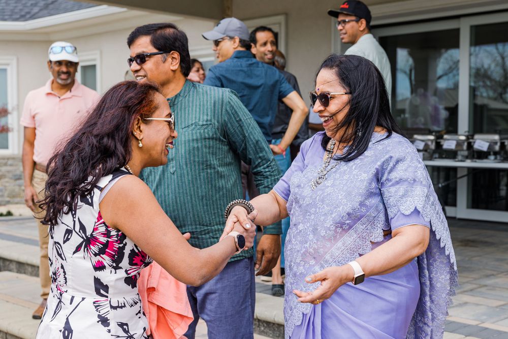 People mingling and greeting each other at an outdoor social gathering.