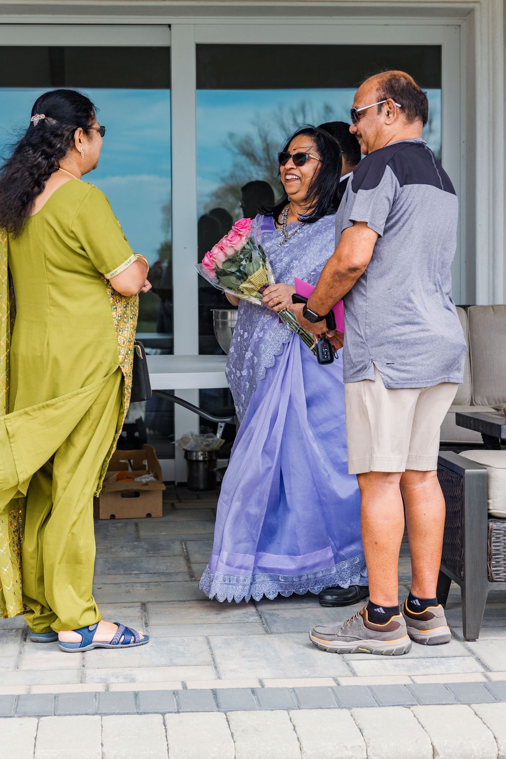 Group of guests chatting and holding flowers during an outdoor celebration.