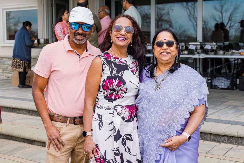 Three people smiling together at an outdoor event wearing colorful summer attire.