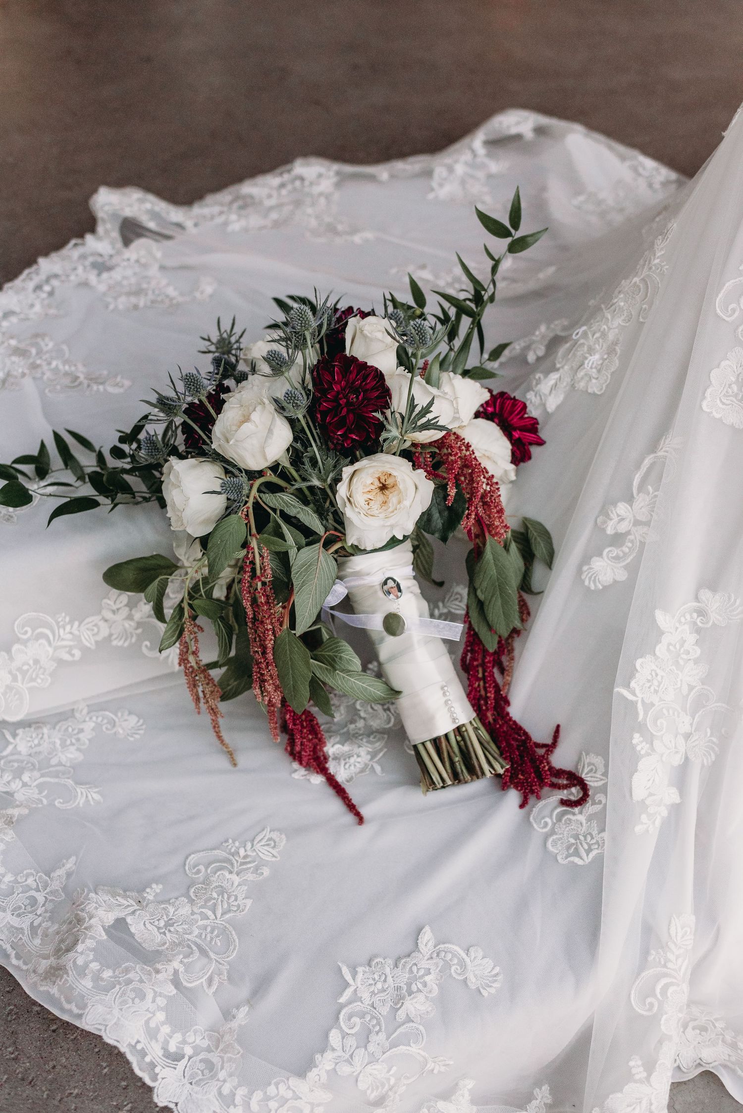 A wedding bouquet with white and burgundy flowers on lace fabric.