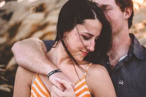 Couple sharing a tender embrace outdoors in warm golden light.