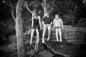 Natural black and white family portraits taken in a wooded outdoor setting.