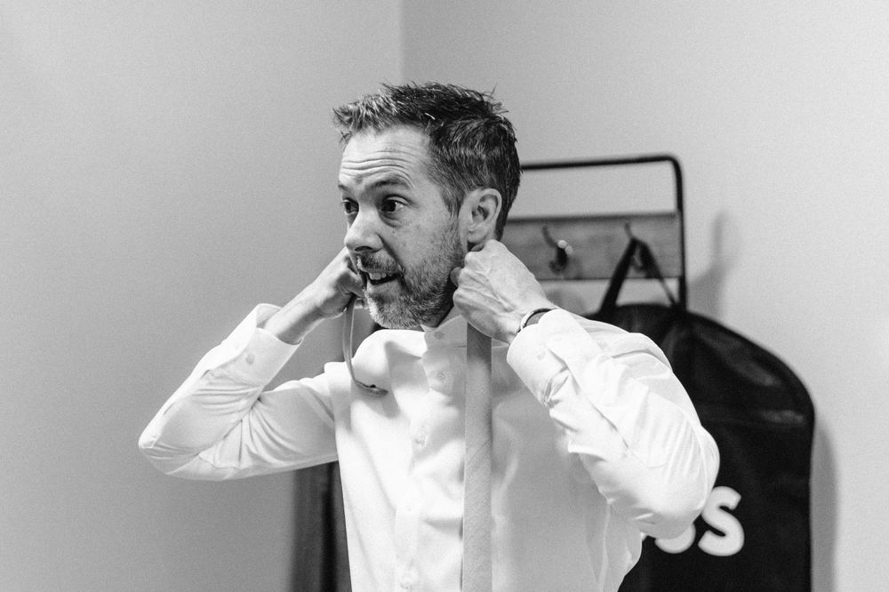 A sequence of mirror reflections showing someone adjusting their tie and white dress shirt.