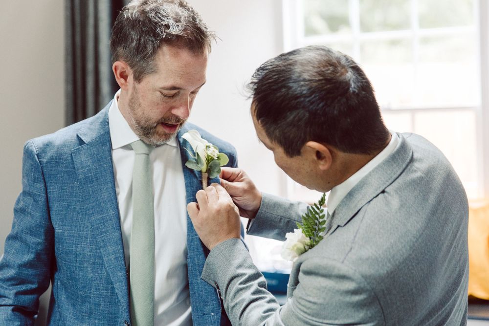 Wedding party members in light blue suits share emotional moments indoors.