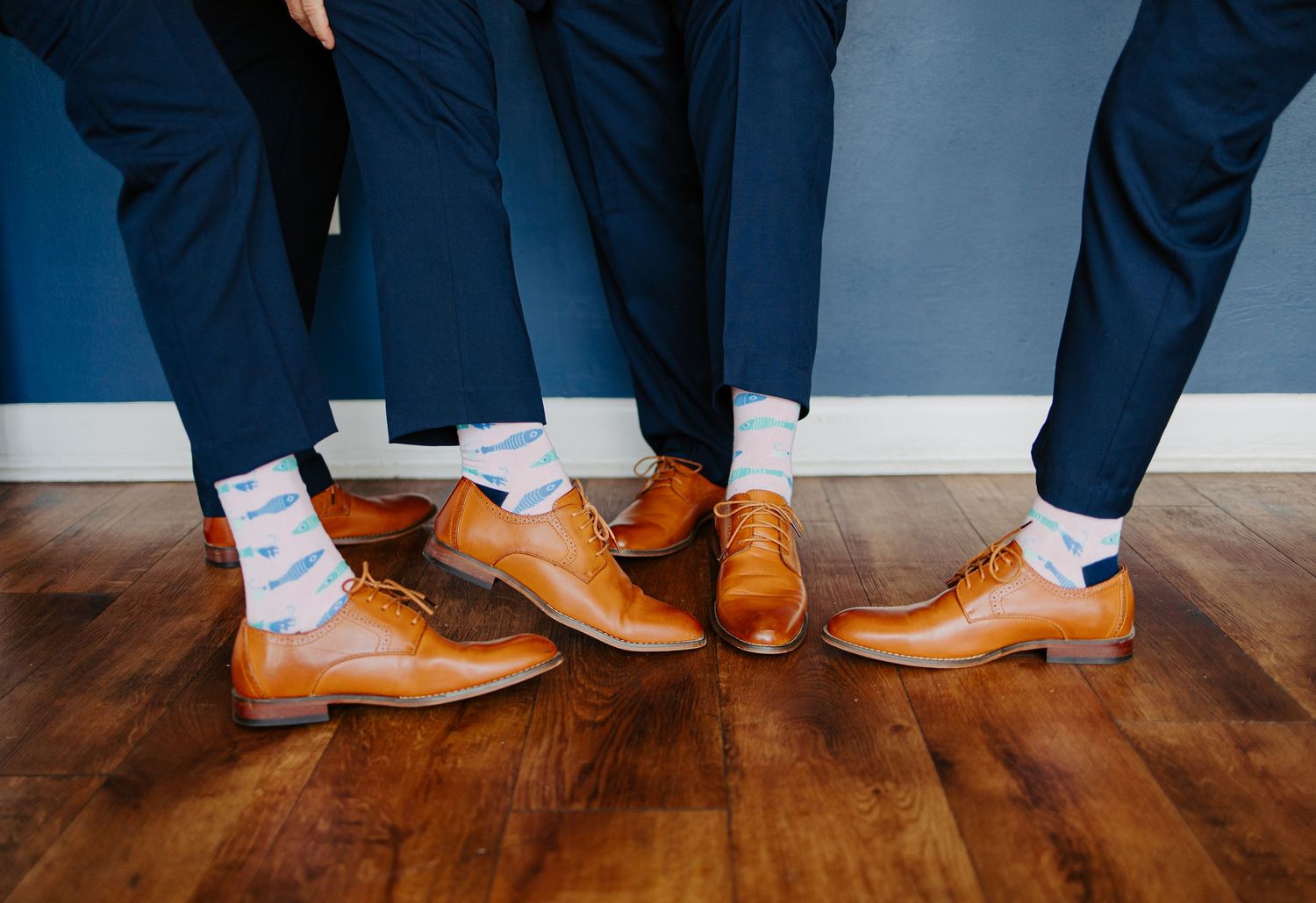 Three groomsmen display matching tan leather oxford shoes and light blue socks.