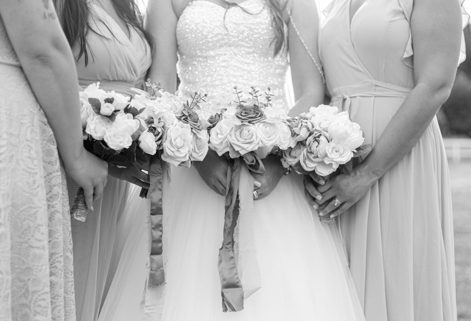 Black and white photo of bride and bridesmaids holding bouquets at wedding ceremony.