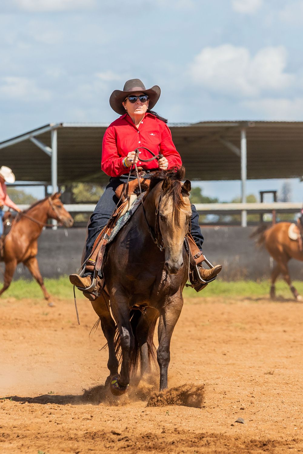 Rider on dark horse performs in dusty rodeo arena during competition.