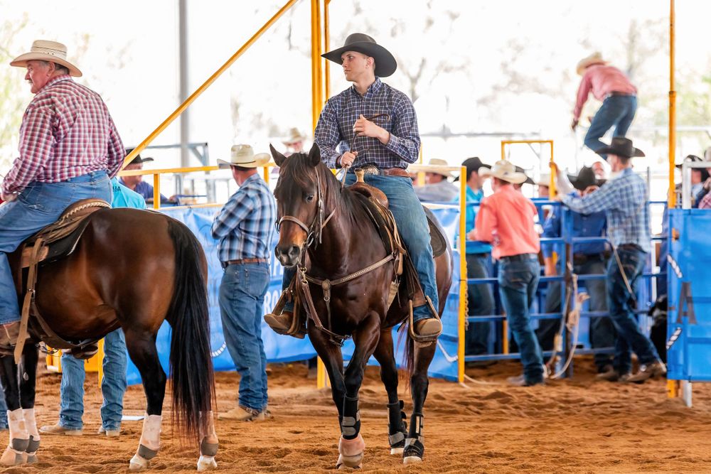 Riders on horseback gather in a rodeo arena surrounded by spectators.
