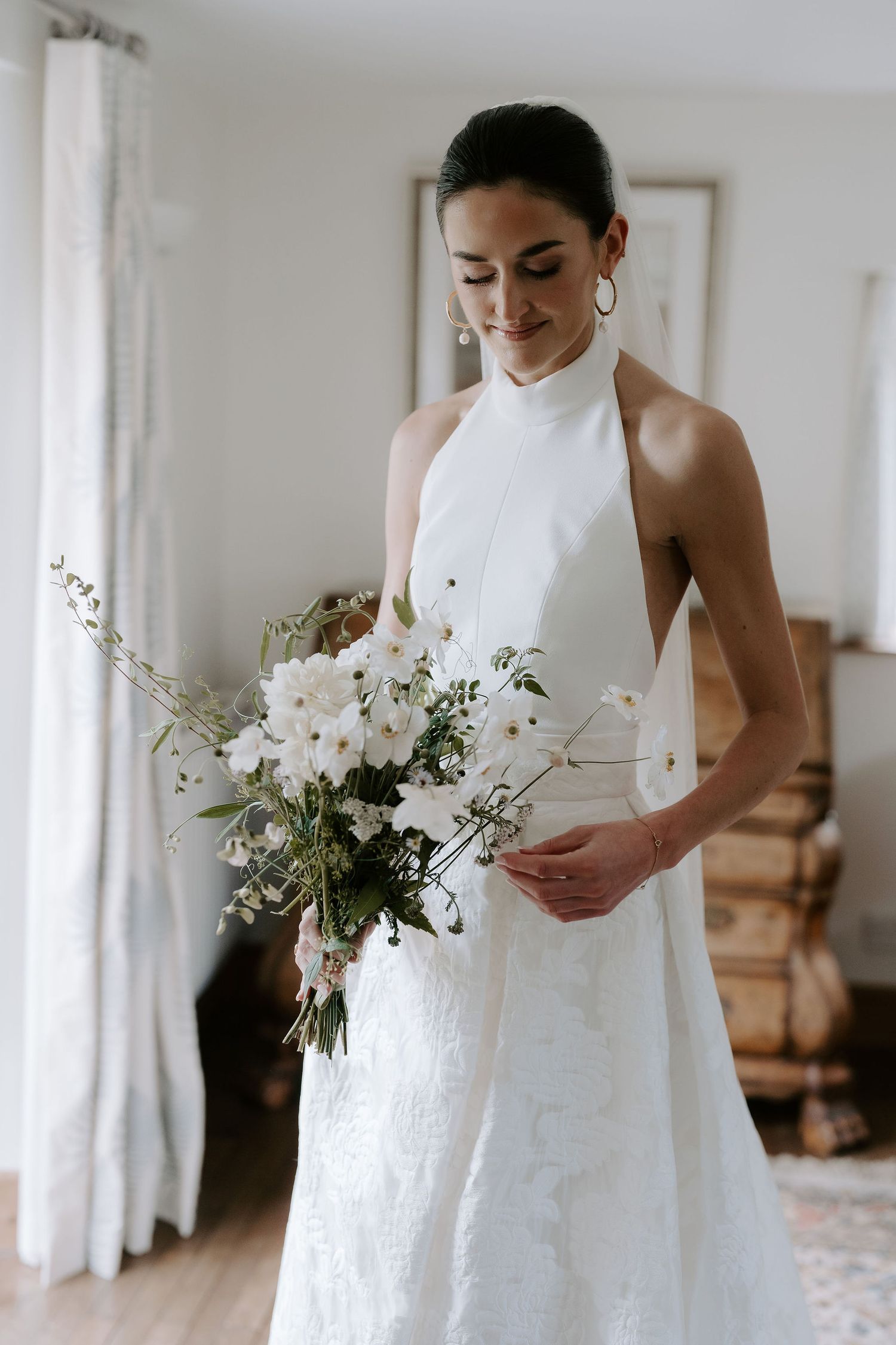 bride looking down at her wedding bouquet before her wedding ceremony in Oxfordshire