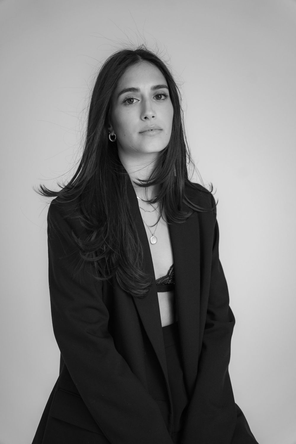 Fashion portrait series in black blazer against white background.