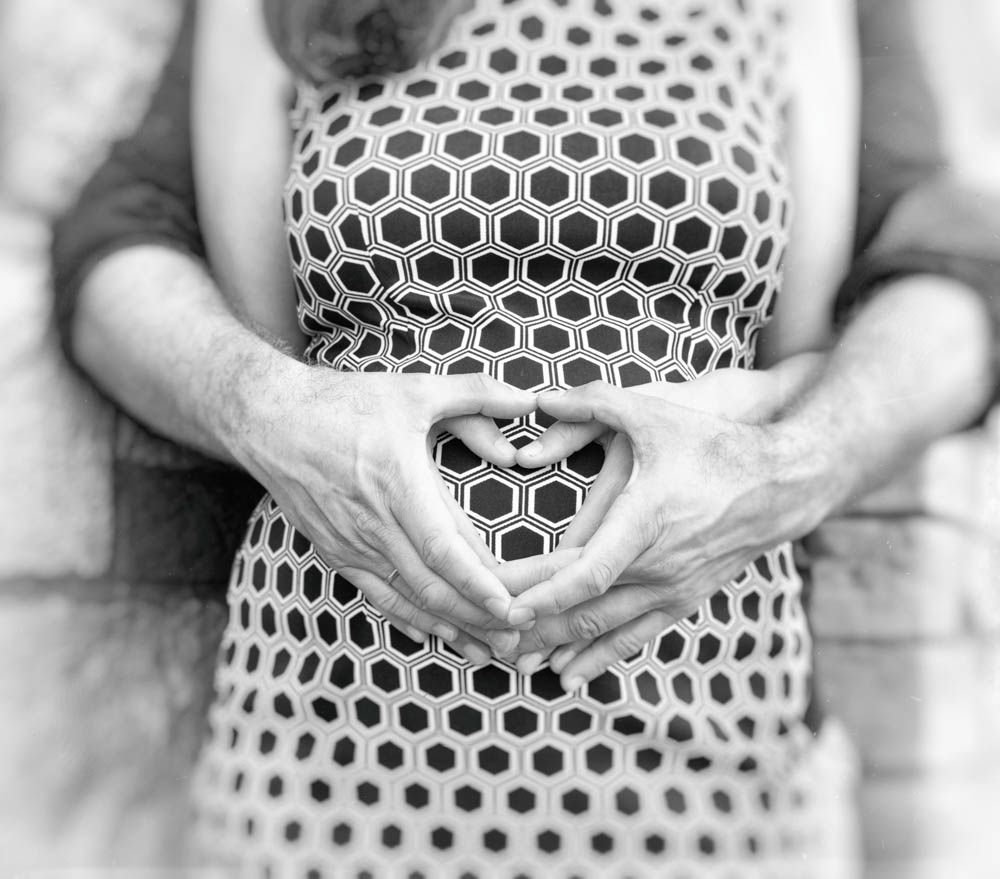 couple making hart with hands on woman belly