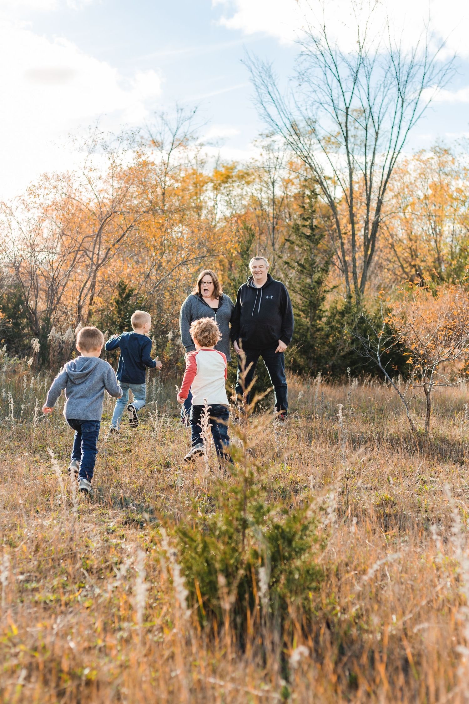 3 boys racing towards their parents in a field
